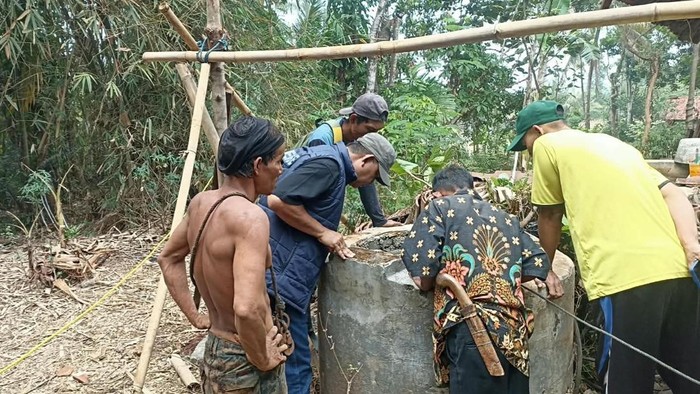 Warga saat mengevakuasi 2 pemuda yang terjebak di dalam sumur kering sedalam 18 meter
