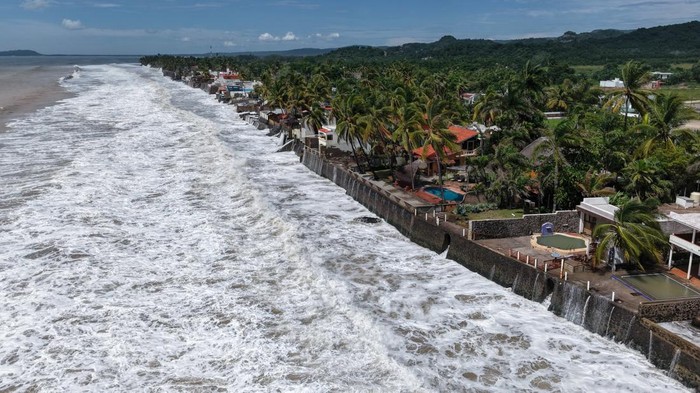 A man walks a bicycle past debris on Aticama Beach as Hurricane Rachel churns off Mexico's Pacific coast, generating high surf and dangerous sea conditions in San Blas, Nayarit state, Mexico, October 1, 2026. REUTERS/Christian Ruano