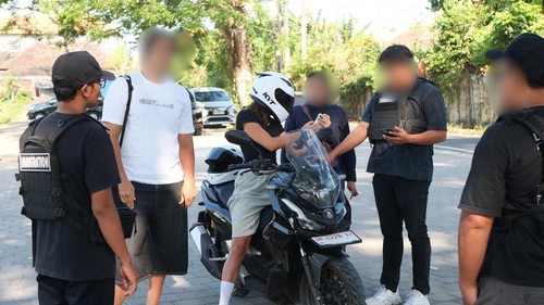 Petugas imigrasi memeriksa dua WNA saat belajar naik motor di kawasan Serangan, Denpasar, Bali. (Foto: Dok. Istimewa)