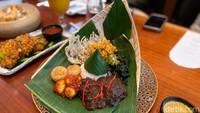 Seporsi Nasi Rendang Jimbaran hadir layaknya nasi rames lengkap. Ada potongan rendang yang disajikan bersama perkedel, telur puyuh balado, hingga rempeyek renyah. Foto: detikFood