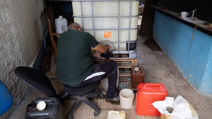 A man pours imported gasoline into a container while another holds a funnel at a private home where the fuel is sold amid a U.S. imposed oil blockade, with an exception allowing U.S. fuel exports to eligible private businesses, in Havana, Cuba, October 2, 2026. REUTERS/Ricardo Arduengo