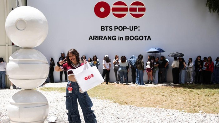 A BTS fan poses with merchandise after visiting the BTS POP-UP : ARIRANG, as other fans wait in line ahead of the South Korean Kpop group's two sold-out concerts at El Campin stadium on October 2 and 3, in Bogota, Colombia, October 1, 2026. REUTERS/Luisa Gonzalez