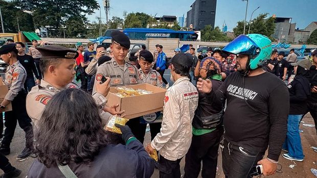 Polisi membagikan air mineral dan roti kepada peserta aksi di depan Gedung DPR, Jakarta Pusat, Selasa (6/10/2026).