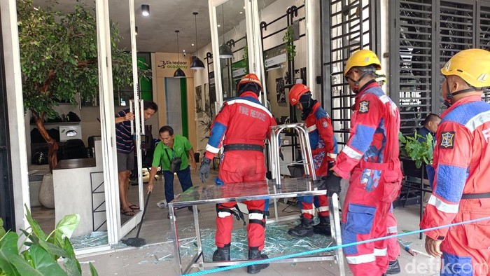 Sejumlah karyawan ruko dibantu petugas rescue BPBD Surabaya membersihkan pecahan kaca imbas leadakan di Pakuwon City Surabaya.