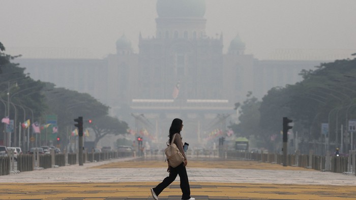 A pedestrian crosses a street as the Prime Ministers Office is shrouded in haze from regional wildfires in Putrajaya, Malaysia, October 7, 2026. REUTERS/Hasnoor Hussain