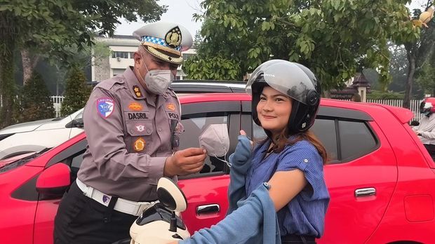 Personel Ditlantas Polda Riau membagikan masker kepada pengendara mengantisipasi kabut asap, Kamis (8/10/2026).