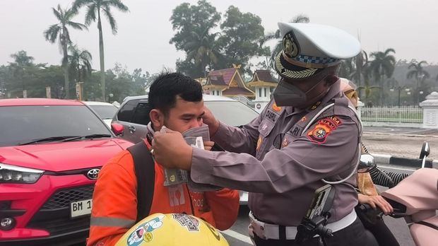 Personel Ditlantas Polda Riau membagikan masker kepada pengendara mengantisipasi kabut asap, Kamis (8/10/2026).