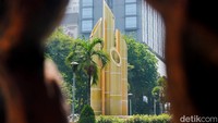 Monumen Bambu Runcing tampak berdiri kokoh di tengah lanskap perkotaan, terlihat dari celah pandangan dengan latar belakang gedung-gedung modern dan pepohonan di pusat Kota Surabaya. Landmark monumen bersejarah ini menghadirkan simbol semangat kepahlawanan yang tetap terjaga di tengah  perkotaan.