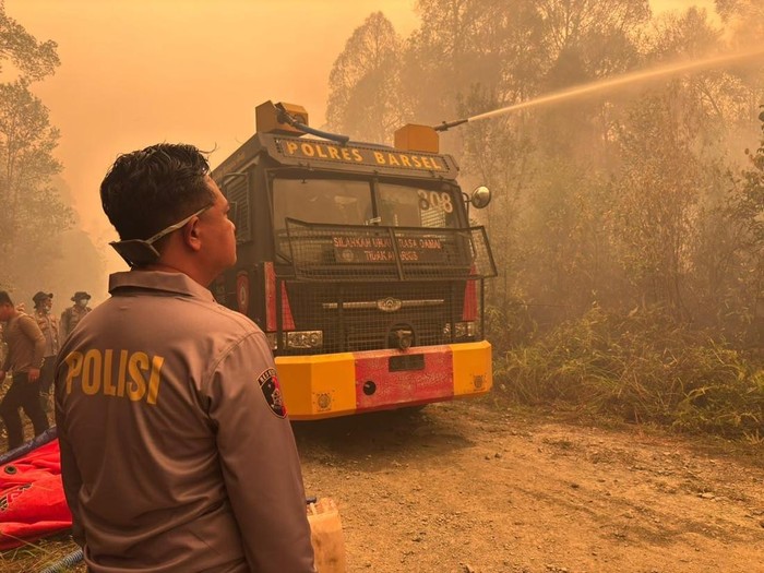 Polisi membantu pemadaman karhutla di tengah pekatnya asap yang membuat langit Barito Selatan menguning. (dok Polres Barsel)