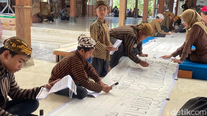Siswa SD Antawirya Islamic Javanese School menuliskan aksara Jawa di atas kain sepanjang 600 meter di Pendopo Giri Kedaton, Junwangi, Krian, Sidoarjo, Minggu (11/10/2026).