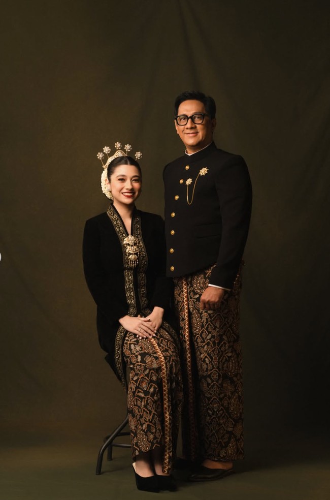 Amanda tampil anggun mengenakan kebaya hitam dengan hiasan bordir berwarna emas di bagian kerah hingga sisi depan. Kebaya tersebut dipadukan dengan kain batik bernuansa cokelat, hitam, dan emas, serupa dengan yang dikenakan Andre. Foto: Instagram/@amandarigby6