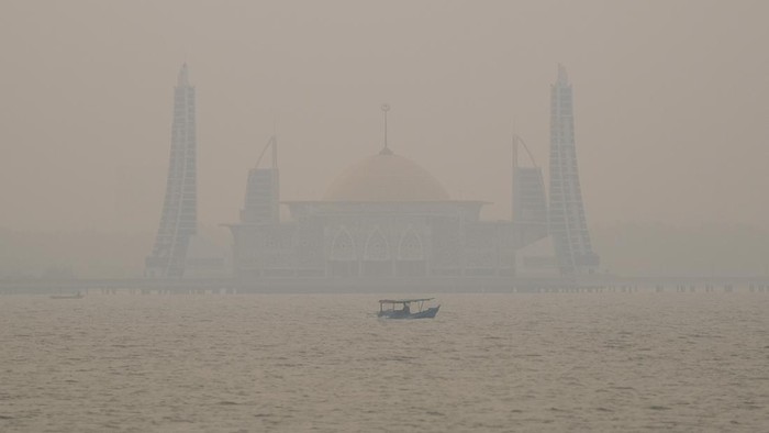Sebuah perahu nelayan melintasi kawasan Masjid terapung Al Alam yang mulai tertutup asap di Kendari, Sulawesi Tenggara, Selasa (13/10/2026). BMKG setempat mengimbau pengguna moda transportasi darat, laut, dan udara di Sulawesi Tenggara agar meningkatkan kewaspadaan terhadap potensi penurunan jarak pandang akibat kabut asap kiriman dari Maluku dan Papua Selatan yang meningkat pada sore hingga malam hari. ANTARA FOTO/Andry Denisah/nz