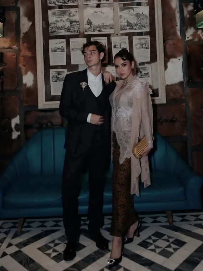 Olla Ramlan tampil anggun mengenakan kebaya brokat bernuansa nude-champagne yang dipadukan dengan kain batik sogan dan selendang. Tristan Molina melengkapi penampilan tersebut dengan setelan jas hitam, rompi, dan kemeja putih. Bros kristal perak memberikan sentuhan mewah pada gaya formalnya. Foto: Instagram/@ollaramlan