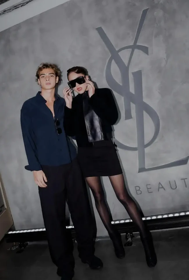 Saat menghadiri acara YSL Beauty, Olla tampil berani dengan jaket kulit hitam, rok mini, stoking transparan, dan sepatu bot hak tinggi. Kacamata hitam berukuran besar serta lipstik merah gelap memperkuat kesan edgy. Tristan menyelaraskan gayanya dengan kemeja biru navy, celana panjang hitam longgar, dan sepatu formal hitam. Foto: Instagram/@ollaramlan