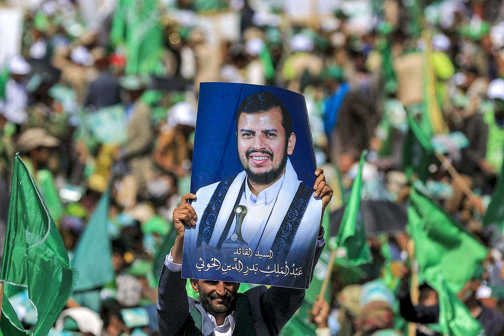 Seorang warga Yaman mengangkat poster pemimpin Houthi, Abdul Malik al-Houthi, dalam sebuah upacara peringatan hari kelahiran Nabi Muhammad di Sanaa pada 27 September 2023. (Photo by MOHAMMED HUWAIS / AFP)