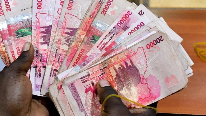 A teller handles Ugandan shilling notes inside the cashier's booth at a forex exchange bureau as the dollar rate continues to escalate in Kampala, Uganda, October 14, 2026. REUTERS/Abubaker Lubowa