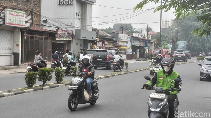 Pengendara roda dua menggunakan masker di jalanan Kota Medan.