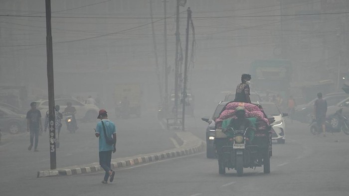 People wearing protective masks ride on a three-wheeled vehicle through a road as haze from wildfires shrouds the area in Palembang, South Sumatra province, Indonesia, October 15, 2026. REUTERS/Abriansyah Liberto
