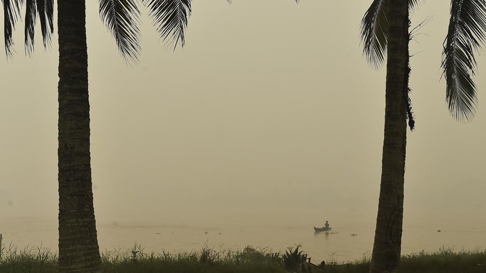Pengendara melintasi Jembatan Berbak yang diselimuti asap kebakaran hutan dan lahan (karhutla) di Kelurahan Simpang, Berbak, Tanjung Jabung Timur, Jambi, Jumat (16/10/2026). Asap karhutla di beberapa kota/kabupaten Provinsi Jambi terpantau bertambah pekat dalam beberapa hari terakhir, terutama Kecamatan Berbak yang berdampingan langsung dengan sumber api Taman Nasional Berbak Sembilang (TNBS) dan Tahura Orang Kayo Hitam (OKH) dan berdasarkan pantauan stasiun Indeks Standar Pencemaran Udara (ISPU) kualitas udara di Tanjung Jabung Timur Jumat (16/10) mencapai angka 331 atau masuk kategori berbahaya. ANTARA FOTO/Wahdi Septiawan/sgd