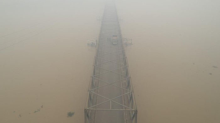 Pengendara melintasi Jembatan Berbak yang diselimuti asap kebakaran hutan dan lahan (karhutla) di Kelurahan Simpang, Berbak, Tanjung Jabung Timur, Jambi, Jumat (16/10/2026). Asap karhutla di beberapa kota/kabupaten Provinsi Jambi terpantau bertambah pekat dalam beberapa hari terakhir, terutama Kecamatan Berbak yang berdampingan langsung dengan sumber api Taman Nasional Berbak Sembilang (TNBS) dan Tahura Orang Kayo Hitam (OKH) dan berdasarkan pantauan stasiun Indeks Standar Pencemaran Udara (ISPU) kualitas udara di Tanjung Jabung Timur Jumat (16/10) mencapai angka 331 atau masuk kategori berbahaya. ANTARA FOTO/Wahdi Septiawan/sgd