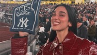 Dua Lipa terlihat memakai mantel kulit bermotif buaya berwarna burgundy. Ia difoto sambil memegang foam finger. (Foto: dok Instagram dualipa)