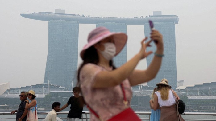 A woman wearing a face mask rides a bicycle as haze shrouds the central business district in Singapore, October 16, 2026. REUTERS/Edgar Su