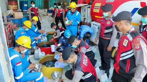 Anggota Ditsamapta Polda Bali membantu penyaluran BBM di SPBU kepada masyarakat.