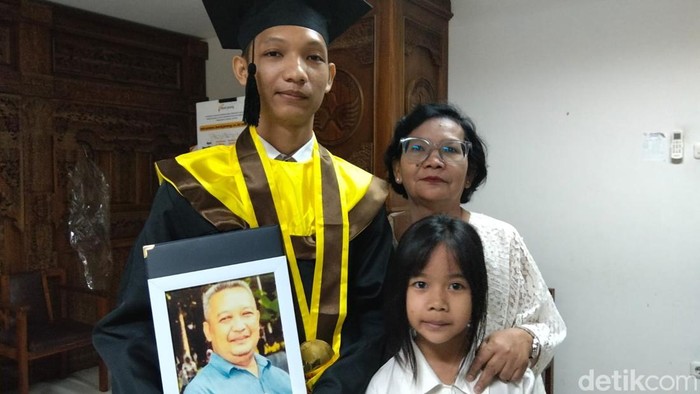 Wisudawan Universitas Tidar (Untidar) jurusan Teknik Mesin, Rafael Christiandinata membawa foto figura bapaknya yang sudah meninggal, Sabtu (17/10/2026).