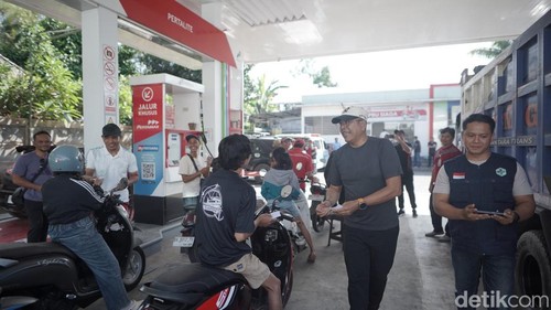 Bupati Karangasem I Gusti Putu Parwata saat membagikan kupon pertalite gratis kepada masyarakat yang antre BBM di SPBU, Minggu (18/10/2026).