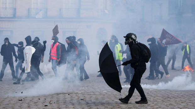 A protester covers behind an umbrella while people take part in a demonstration as part of nationwide protests called by the 