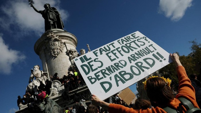 A protester holds a placard reading Efforts must be made. Starting with Bernard Arnault near the Marianne statue of the Place de la Republique during a demonstration against the cost of living and rising fuel prices in Paris as part of nationwide p