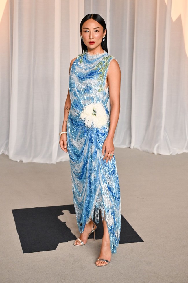 Greta Lee mengenakan gaun Dior Haute Couture koleksi Autumn-Winter 2026&ndash;2027 berbahan sifon sutra putih dengan sulaman payet bermotif langit. Detail rumbai berpayet dan ornamen bunga eukaliptus besar di pinggul menciptakan kesan artistik pada penampilannya. (Foto: Getty Images)