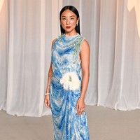 Greta Lee mengenakan gaun Dior Haute Couture koleksi Autumn-Winter 2026&ndash;2027 berbahan sifon sutra putih dengan sulaman payet bermotif langit. Detail rumbai berpayet dan ornamen bunga eukaliptus besar di pinggul menciptakan kesan artistik pada penampilannya. (Foto: Getty Images)