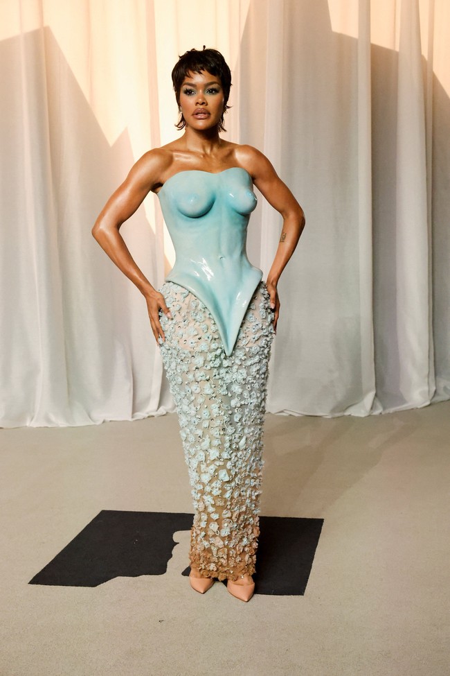 Teyana Taylor berbalut gaun Schiaparelli Haute Couture koleksi Fall 2026 dengan bustier keramik yang menjadi pusat perhatian. Rok transparan berhias bunga-bunga tulle dan detail kristal memberikan kesan artistik sekaligus dramatis. (Foto: REUTERS/Mario Anzuoni)