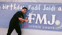 Fadil Jaidi berfoto di spanduk bertuliskan FMJ Tennis Court. Ia yang memakai setelan pakaian serba hitam terlihat begitu bahagia. (Foto: Instagram @fadiljaidi)