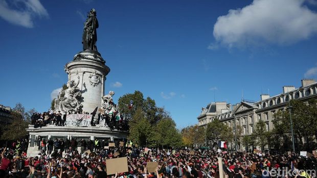 Protesters stand on the Marianne statue of the Place de la Republique during a demonstration against the cost of living and rising fuel prices in Paris as part of nationwide protests called by the