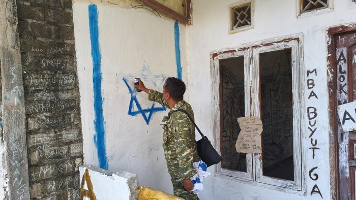 Petugas mencopot dan membersihkan mural bendera Israel yang dipasang di rumah warga di Made, Lamongan