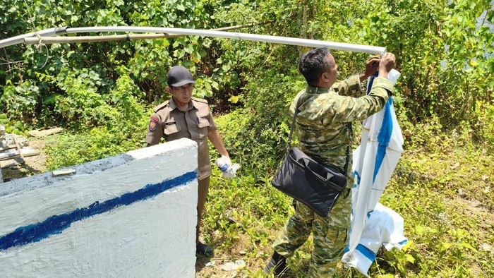 Petugas mencopot dan membersihkan mural bendera Israel yang dipasang di rumah warga di Made, Lamongan