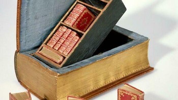 Miniatur Buku di Dalam Kotak Bentuk Buku (Tahun 1736). Buku besar antik yang dibuka untuk memperlihatkan kompartemen rahasia berisi tumpukan buku-buku mini merah karya Suenonius Mandelgreen. Foto: Boredpanda
