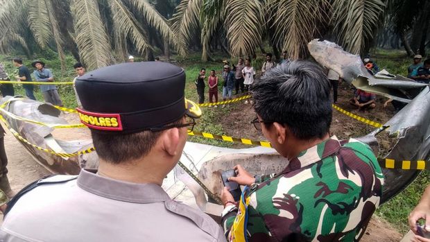 INDONESIA-CHINA-ACCIDENT-SPACE-ROCKET This picture taken on October 19, 2026 shows Indonesian police officers and a military personnel examining a large charred metallic fragment, suspected to be rocket debris, at an oil palm plantation in East Kotawaringin Regency, in Indonesia's Central Kalimantan province. Indonesian authorities were investigating October 20 after a piece of rocket the size of a car crashed into an oil palm plantation on Indonesian Borneo. (Photo by AHMAD SYIHAB / AFP)