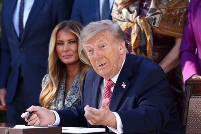 Trump membubuhkan tanda tangan dengan spidol, lalu berseloroh dan mengejek tanda tangan Melania di depan para pejabat.  Saya tidak tahu apakah tanda tangannya ada artinya,” katanya mengejek. Foto: REUTERS/Kevin Lamarque