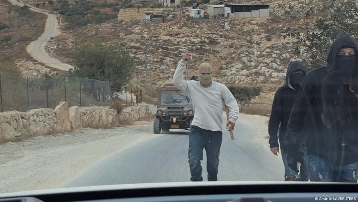 Sejumlah orang bertopeng berada di lokasi dugaan serangan pemukim Israel terhadap warga Palestina, perwakilan Katolik, serta diplomat dan pejabat Barat di Taybeh, Tepi Barat yang diduduki Israel (Amit Orfali/REUTERS)