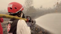 Riyuka mencoba memegang langsung selang penyemprot air ke lahan yang masih mengeluarkan asap. Foto: Instagram @riyukabunga