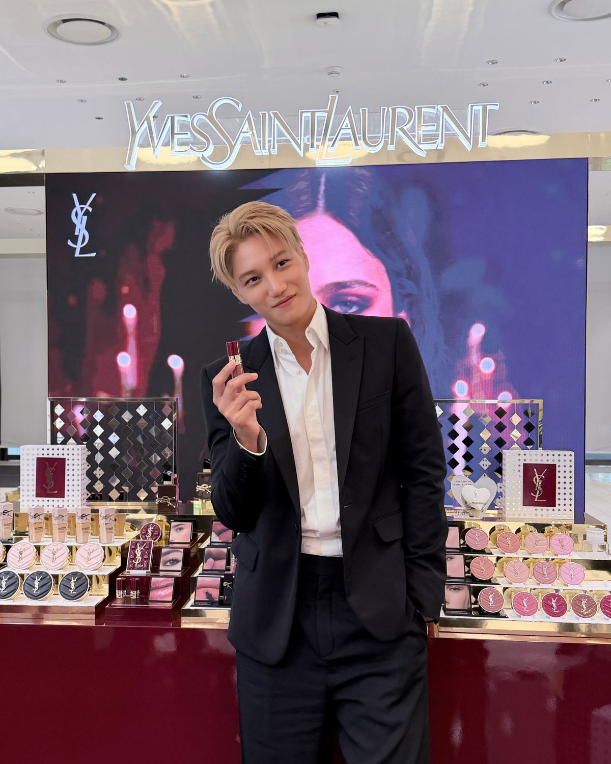 ソウルのYSL Beautyイベントで、黒いスーツ姿でリップ製品を手にする金髪のカイ