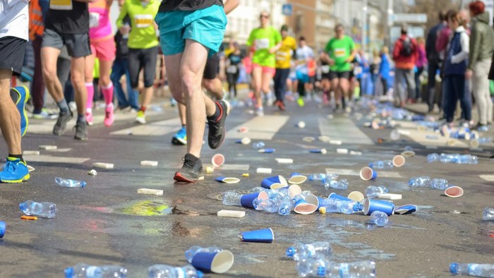 Marathon running race, runners feet and plastic water cups on road near refreshment point, sport, fitness and healthy lifestyle concept