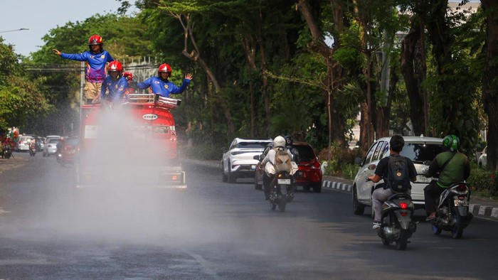 Petugas Damkar menyemprot jalanan di Surabaya demi mengatasi panas dan debu proyek yang bikin warga beraktivitas tidak nyaman.