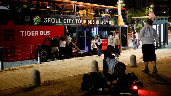 Participants watch actors dressed as zombies perform beside a bus during the Seoul City Tour Bus Zombie Attack event ahead of Halloween in Seoul, South Korea, October 21, 2026. REUTERS/Kim Soo-hyeon