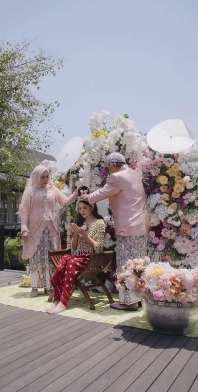 Terlihat kedua orangtua Yuriska bersama-sama menyiram putrinya dengan air khusus yang diambil dari 7 sumber mata air berbeda.&nbsp;Foto: Instagram/@bumitarate