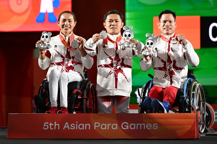 Tim para angkat berat Indonesia Ni Nengah Widiasih (kiri), Hilman (tengah) dan Abdul Hadi (kanan) berpose menunjukkan medali yang diraih dalam pertandingan para angkat berat nomor Mixed Team Asian Para Games 2026 di Nagoya City Trade & Industry Center, Nagoya, Jepang, Sabtu (24/10/2026). Tim Indonesia meraih medali perak setelah di partai final kalah dari tim Irak. NPC INDONESIA/Agung Wahyudi