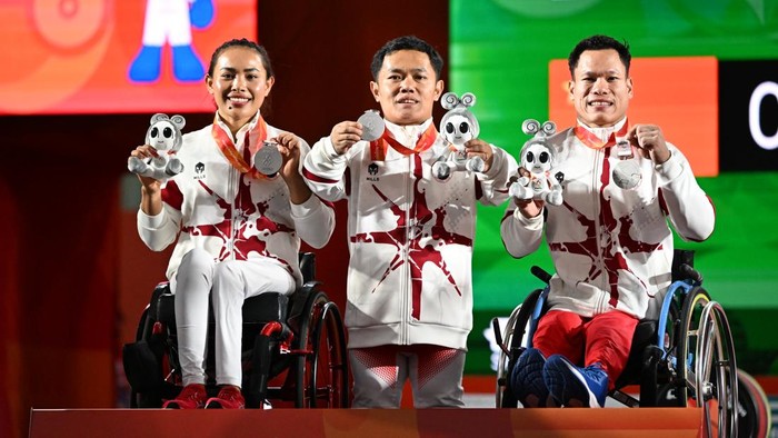 Tim para angkat berat Indonesia Ni Nengah Widiasih (kiri), Hilman (tengah) dan Abdul Hadi (kanan) berpose menunjukkan medali yang diraih dalam pertandingan para angkat berat nomor Mixed Team Asian Para Games 2026 di Nagoya City Trade & Industry Center, Nagoya, Jepang, Sabtu (24/10/2026). Tim Indonesia meraih medali perak setelah di partai final kalah dari tim Irak. NPC INDONESIA/Agung Wahyudi